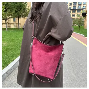 Detailansicht der burgunderroten Bucket Bag mit verstellbarem Gurt am braunen Mantel