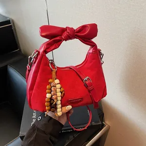 Red dumpling handbag with oversized bow handle and decorative beads on a black leather chair