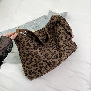 Dettaglio della borsa tote leopardata con manici in pelle marrone su fondo denim