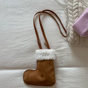 Detail of Christmas stocking shaped crossbody bag featuring faux suede and fuzzy trim