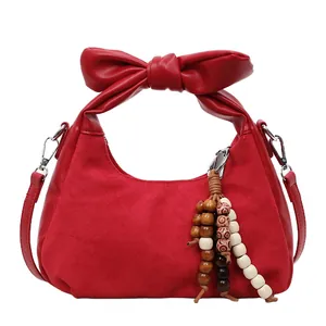 Red dumpling shoulder bag with large bow handle and ethnic wooden bead charm detail
