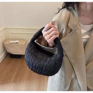 Close-up of black quilted puffer handbag with semi-circle silhouette and zipper detail