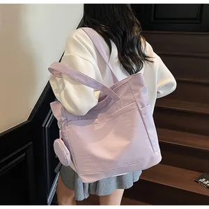 Back view of a model wearing a large lavender canvas tote bag with a small coin pouch