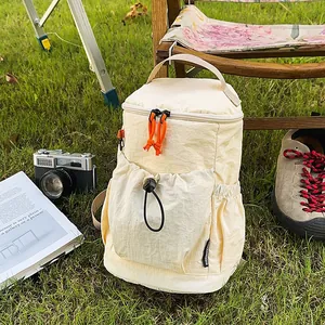 Detail eines cremefarbenen Nylon-Rucksacks mit orangefarbenen Zügen und Kordelzugtasche im Freien