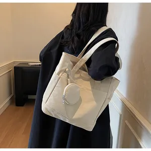 Detail of minimalist cream canvas tote bag with JUMAITU leather patch and matching coin purse