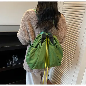 Detail des grünen Kordelzug-Rucksacks mit Seitentaschen und gelben Zierschnüren