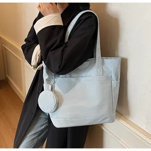 Detail of light blue canvas tote bag featuring side pockets and a round coin purse charm