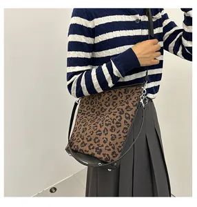 Detail einer Leopard-Tote-Bag mit schwarzen Lederriemen und silbernen Metallhaken