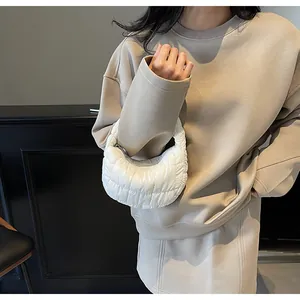 Close-up of white quilted crescent bag showing puffer texture and urban shoulder style
