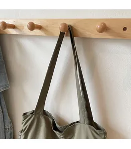 Detail of comfortable wide shoulder strap on an olive green tote bag hanging on a hook