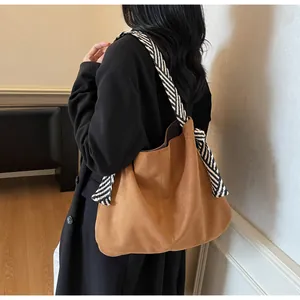 Brown suede tote bag detail with stylish black and white diagonal striped wide shoulder strap