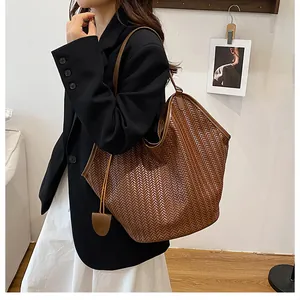 Dettaglio della borsa tote intrecciata marrone con motivo a spina di pesce su modella
