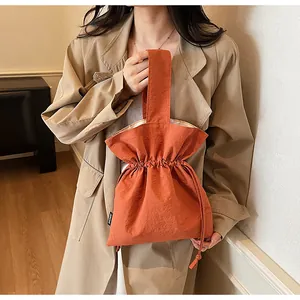 Detail van helder oranje handtas met trekkoordsluiting van waterafstotende nylon stof