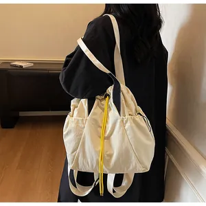 Detailansicht eines cremefarbenen Rucksacks mit gelbem Kordelzug an einem Model