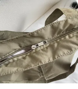 Detailed close-up of smooth metal zipper on olive nylon tote bag with precise stitching