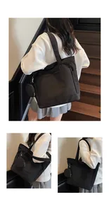 Detail of black tote bag with shoulder strap, front pocket and matching round coin purse