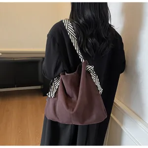 Brown suede tote bag featuring a decorative black and white striped knot shoulder strap