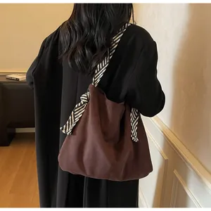 Detail of dark brown suede tote with knotted black and white diagonal stripe strap