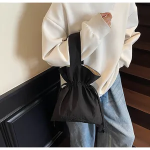 Detail van minimalistische zwarte nylon emmertas met trekkoord en handvat bovenop