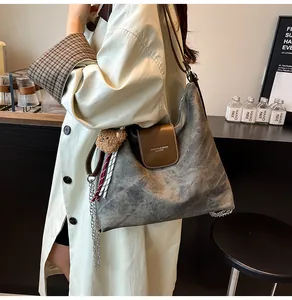 Détail du sac cabas vintage gris avec rabat en cuir marron et breloque ours en peluche