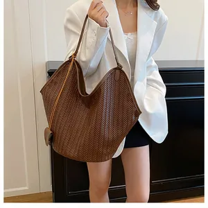 Dettaglio macro della borsa tote in pelle intrecciata marrone scuro con trama fine