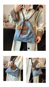 Détails du sac fourre-tout bleu denim avec rabat en cuir brun et breloque ours