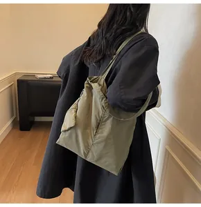 Detailed view of an olive green nylon tote bag with a matching small zipper pouch attached
