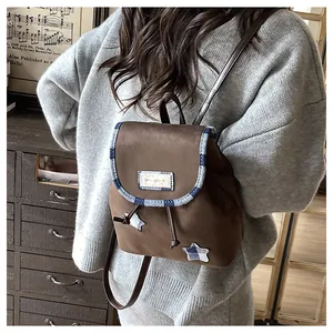 Detail of vintage brown mini backpack featuring plaid star patches and drawstring closure