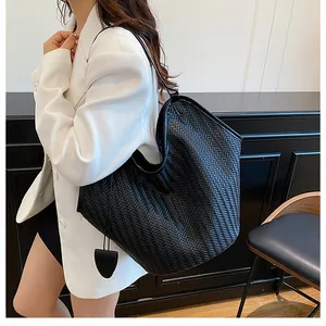 Dettaglio della borsa tote intrecciata nera con un ciondolo decorativo a scudo