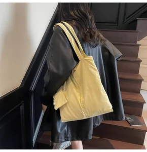 Detail of light yellow canvas tote bag with side pocket shown in casual outfit styling
