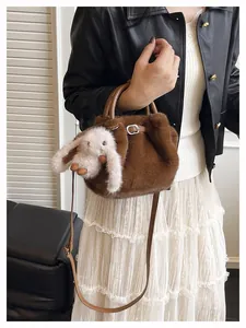 Détail d'un sac seau en peluche marron avec pendentif lapin et bandoulière