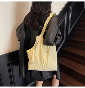 Detail of light yellow nylon tote bag with small zipper pouch and wide shoulder strap