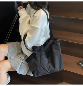 Detail of black large-capacity tote bag with detachable mini pouch on nylon strap