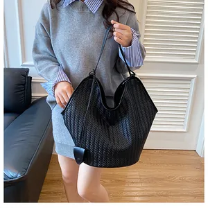 Dettaglio della trama intrecciata su una grande borsa tote nera indossata