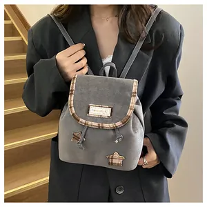 Detail of grey suede mini backpack with star appliques and plaid trim on a wooden staircase