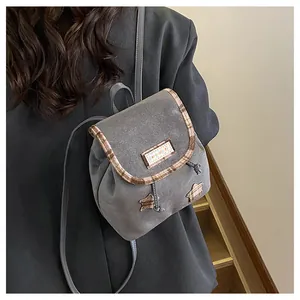 Detail of grey mini backpack featuring star patches and checkered pattern trim accents