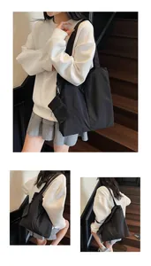 Close-up of black nylon tote bag with small detachable pouch on a wooden staircase