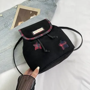 Macro detail of mini black canvas backpack with plaid star patches and drawstring