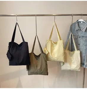 Assorted minimalist tote bags in black, green, yellow, and beige with matching pouches