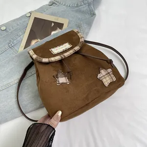 Detail of vintage brown drawstring backpack featuring star patches and textured suede fabric