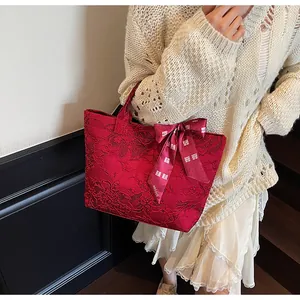 Dettaglio della borsa tote in jacquard rosso con fiocco e decorazione tradizionale