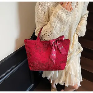 Dettaglio borsa tote rossa in jacquard con motivi floreali e fiocco portafortuna