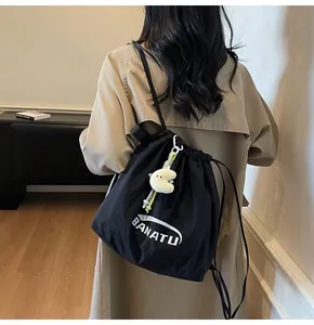 Detail of black nylon drawstring backpack with BANATU logo and yellow plush pendant