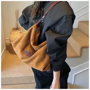 Detail of brown suede hobo bag with deep brown leather strap and metal hook accents