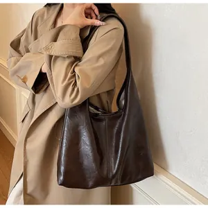 Borsa tote marrone scuro indossata da una modella con dettagli in pelle testurizzata