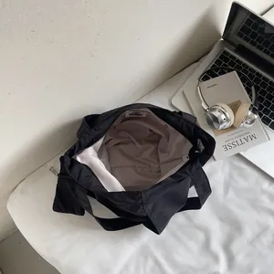 Large black nylon tote bag with wide handle and matching pouch on an office desk