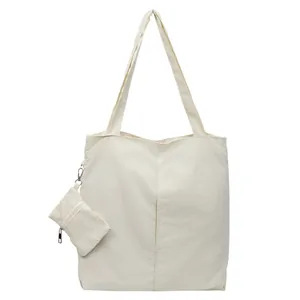 Minimalist ivory tote bag with long straps and matching small pouch for daily commute
