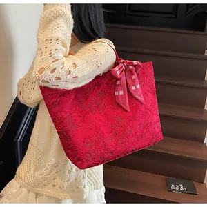 Dettaglio ravvicinato di una borsa tote in jacquard rosso con motivi floreali e fiocco in seta