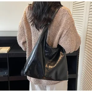 Dettaglio della borsa tote in pelle nera lucida con texture stropicciata e grande capienza