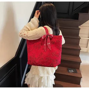 Dettaglio della borsa tote in pizzo rosso con fiocco e ricamo floreale in rilievo